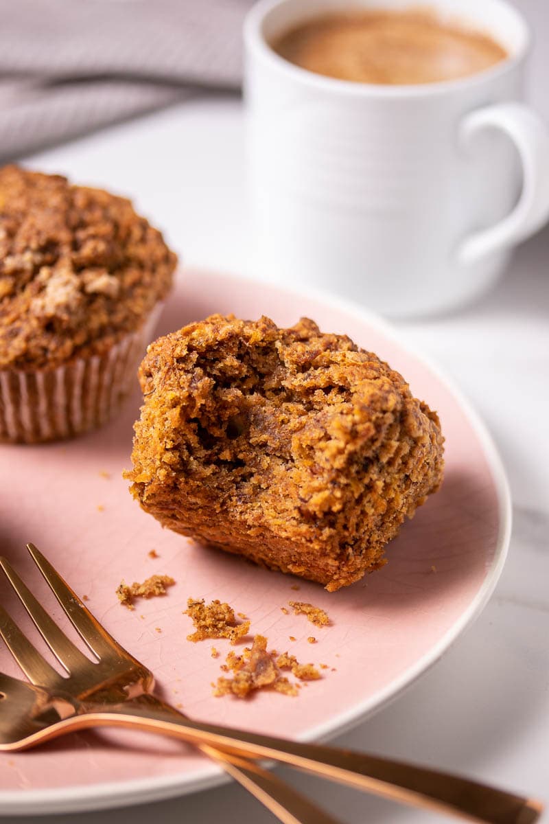 Healthy carrot cake muffins on a plate with one bite taken