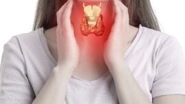 Woman holding her throat and showing where her thyroid is