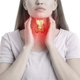 Woman holding her throat and showing where her thyroid is