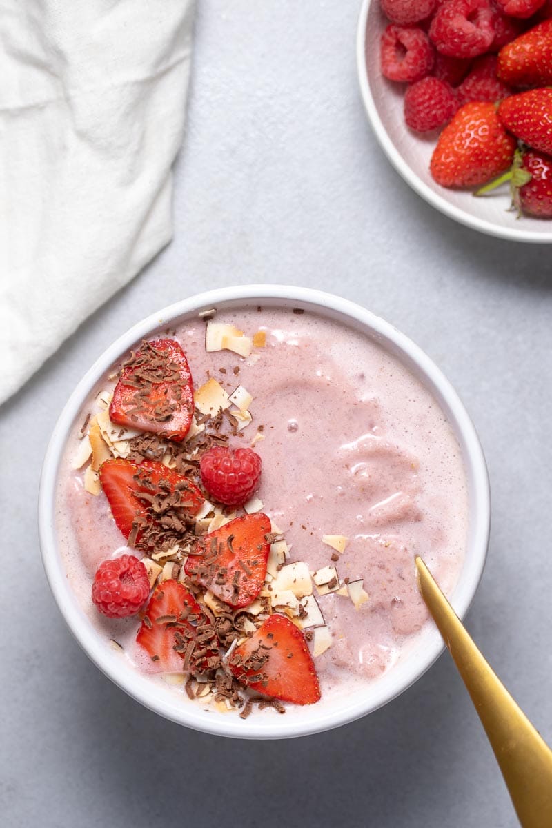Low-Carb Smoothie Bowl with strawberries, cacao nibs, and coconut flakes as seen from above