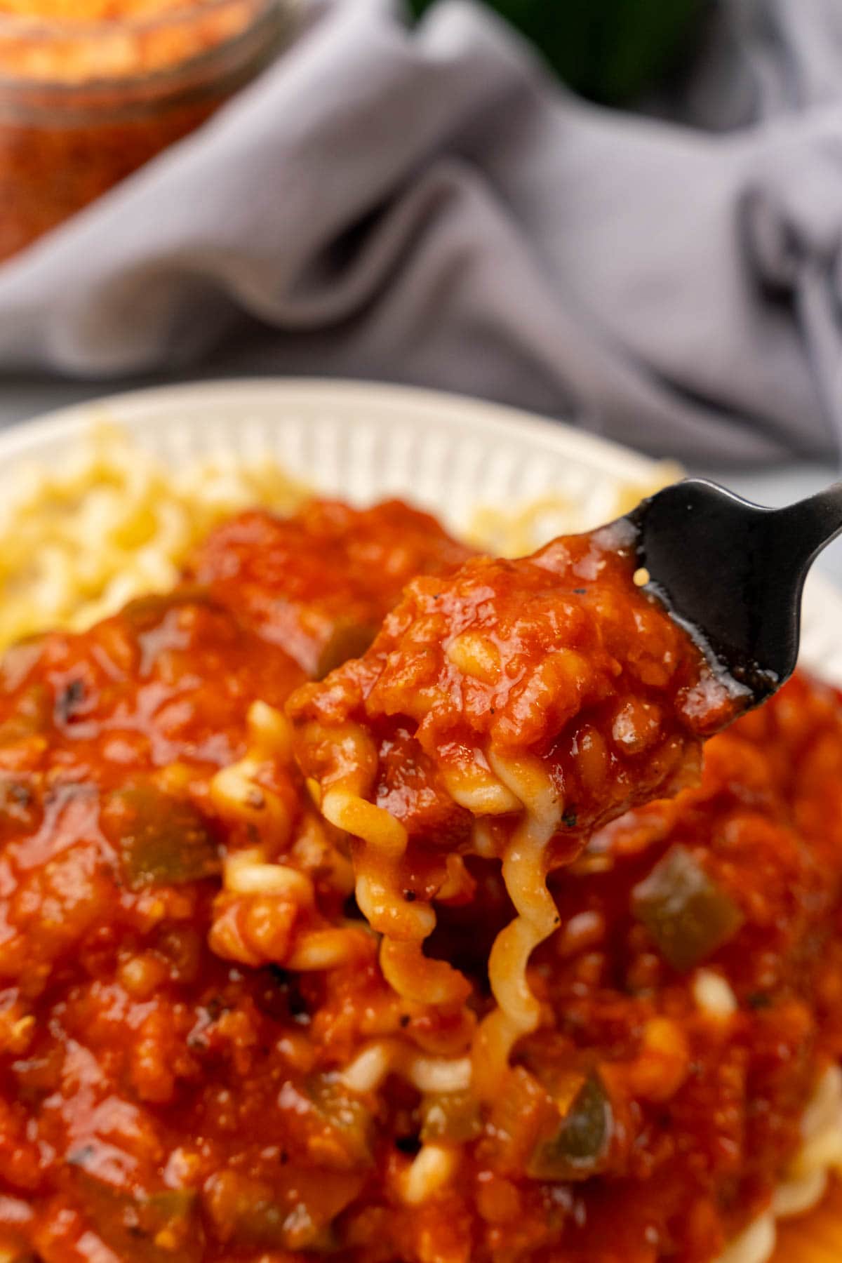 Fork holding vegan noodles covered in marinara sauce