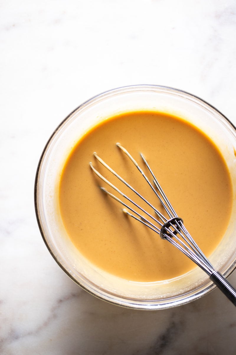 Creamy peanut butter mixture in a bowl with a whisk