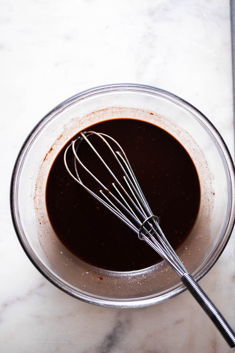 Silky chocolate ganache in a bowl with a whisk