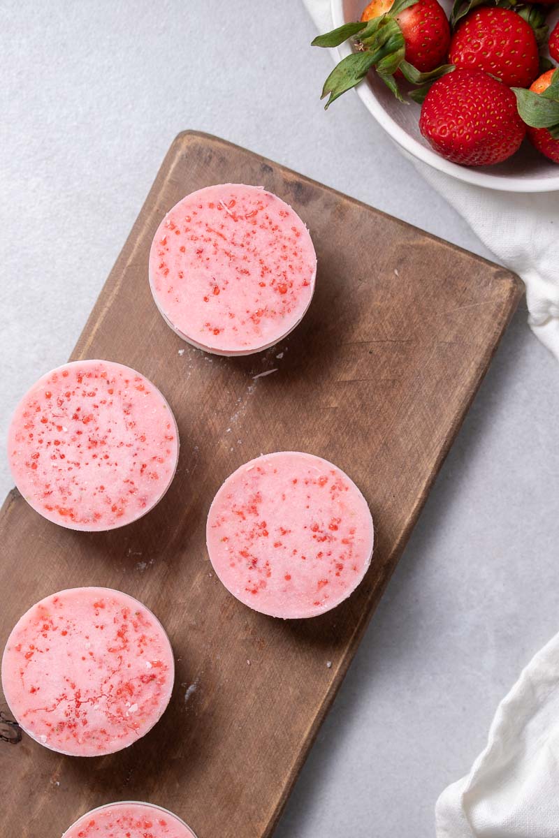 Strawberry Cheesecake Fat Bombs on a wooden board as seen from above