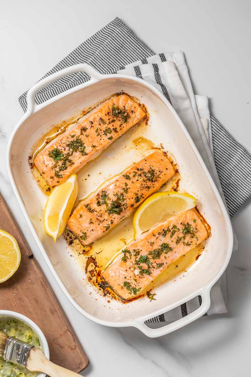 Finished salmon fillets in the baking tray with lemon wedges