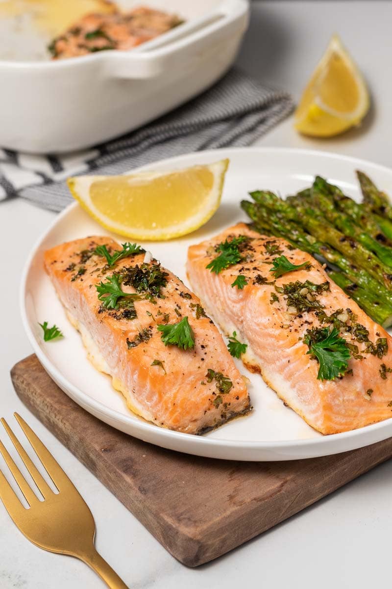 Close-up of two salmon fillets on a plate with asparagus and a lemon wedge