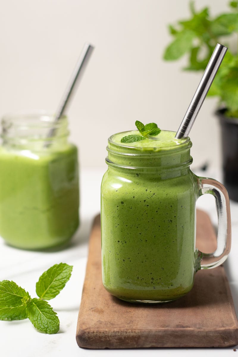 Green smoothie served in a glass with a metal straw