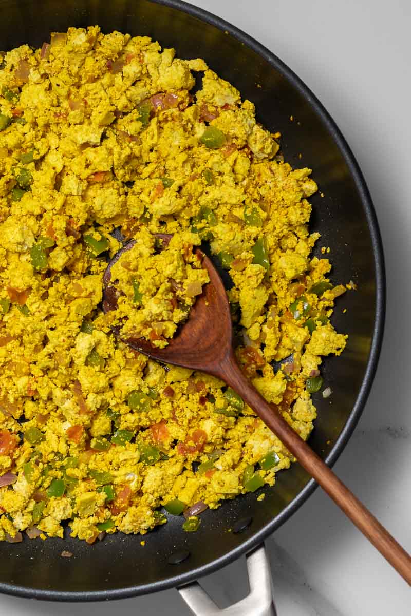 Close-up of pan with cooked scramble and a wooden spoon