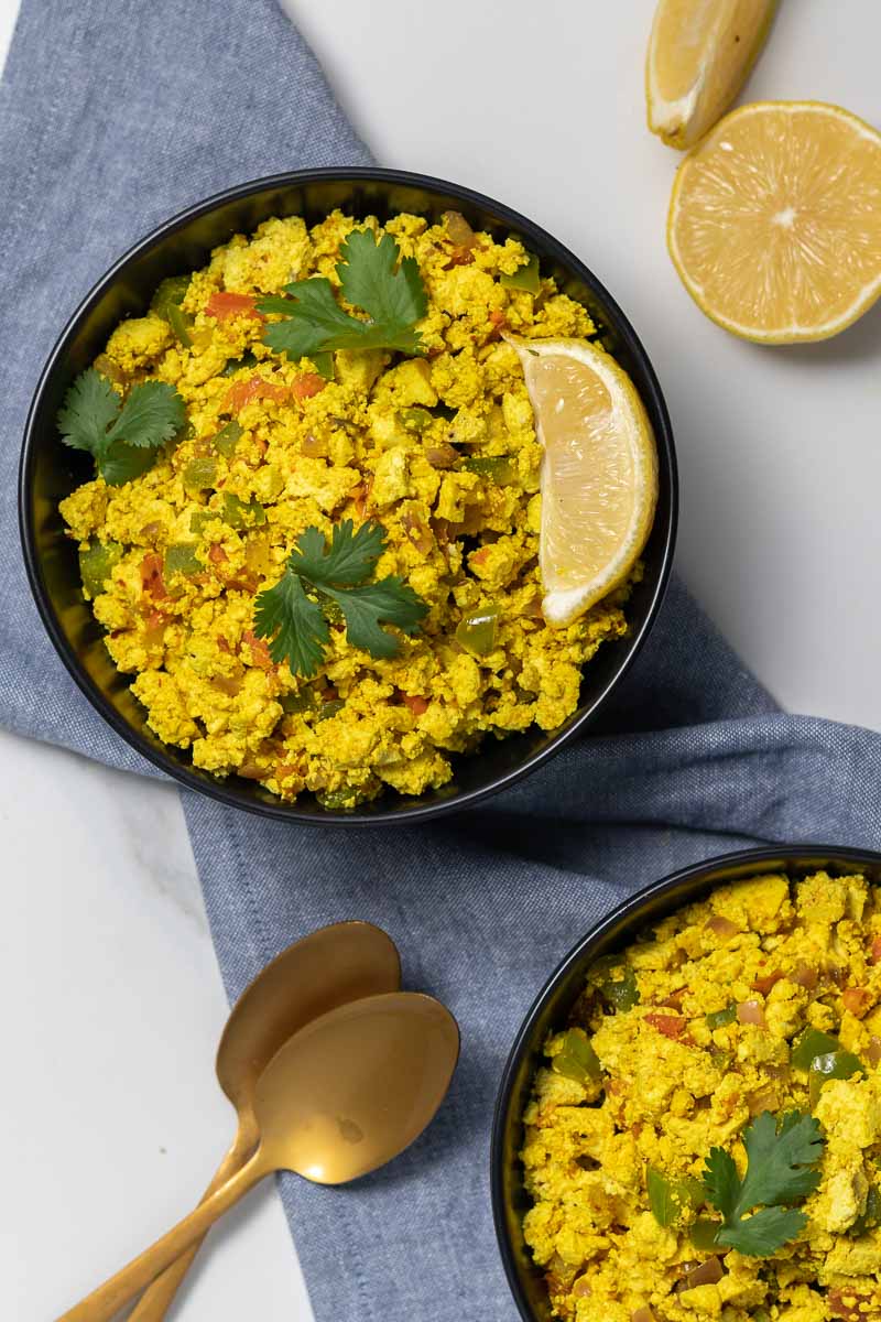 Tofu scramble served in 2 bowls and garnished with cilantro and a lemon wedge