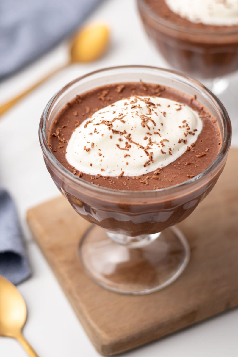 Chilled pudding in a glass and topped with whipped cream and chocolate shavings, ready to be served