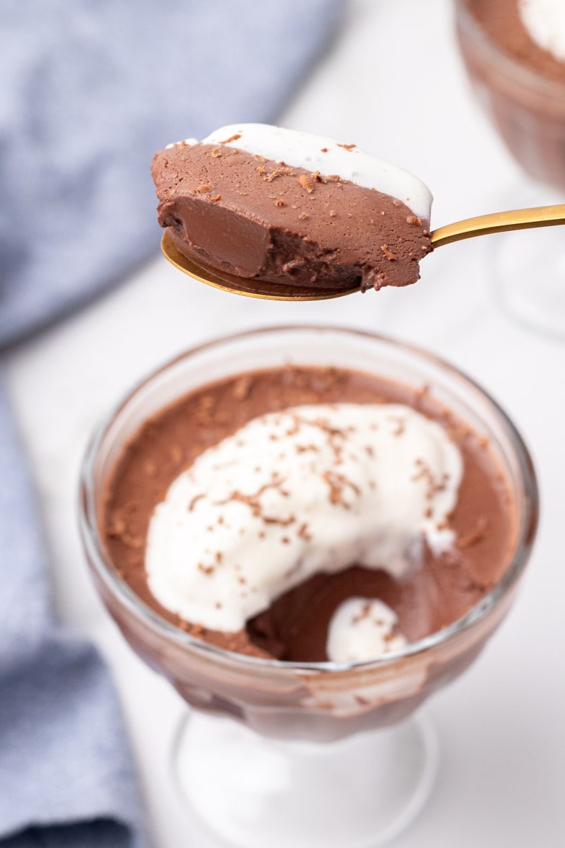 Spoonful of chocolate pudding held over a glass of pudding