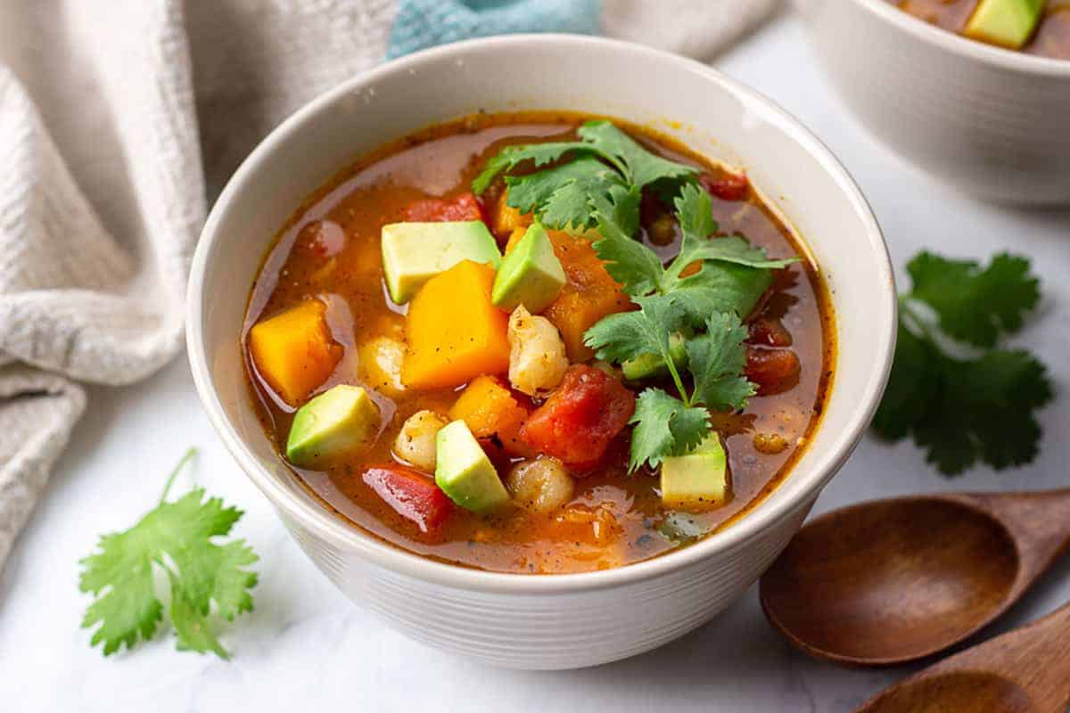 Butternut Squash Posole in a bowl topped with chopped avocado and cilantro