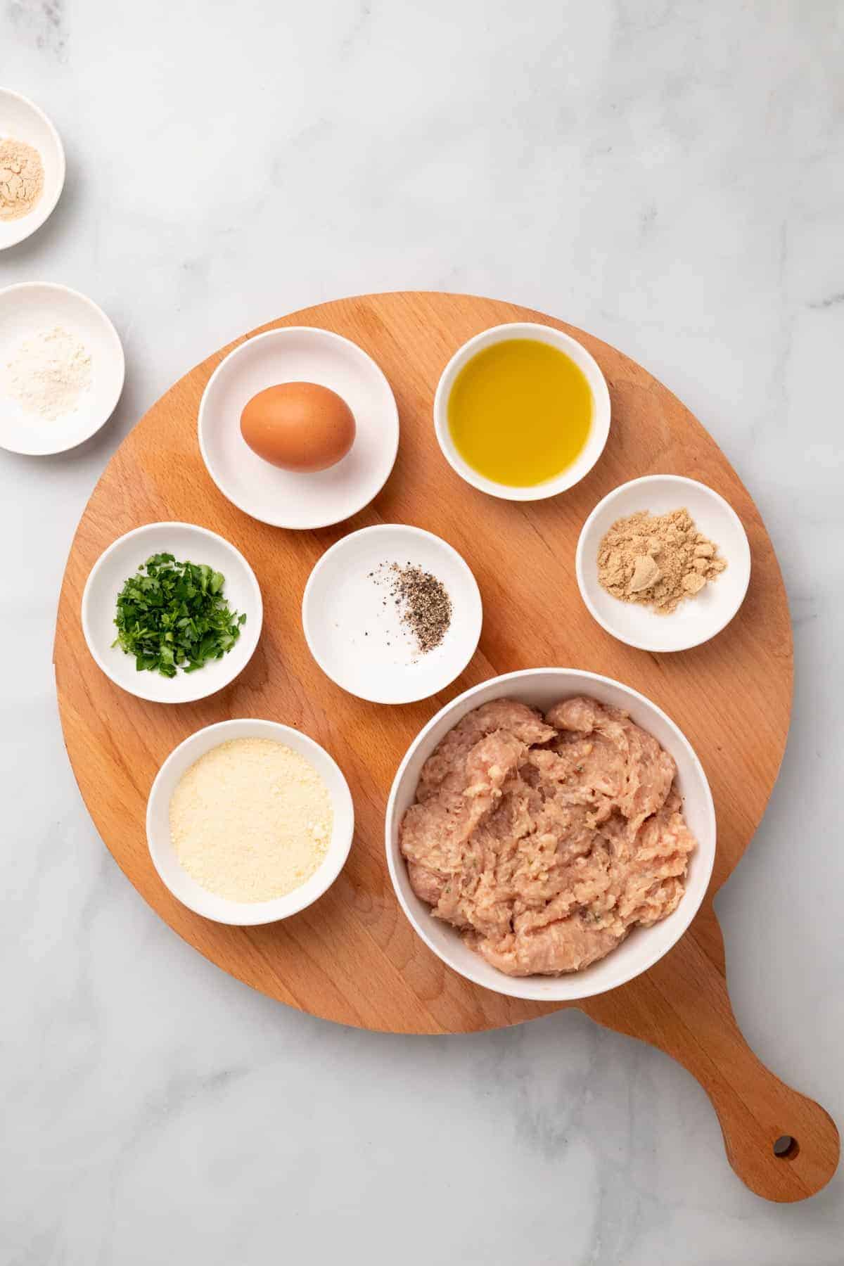 Ingredients for meatballs in separate ramekins and dishes, as seen from above
