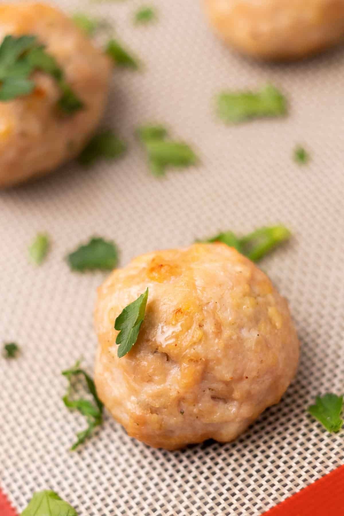 Close-up of meatball on the baking tray, garnished with parsley