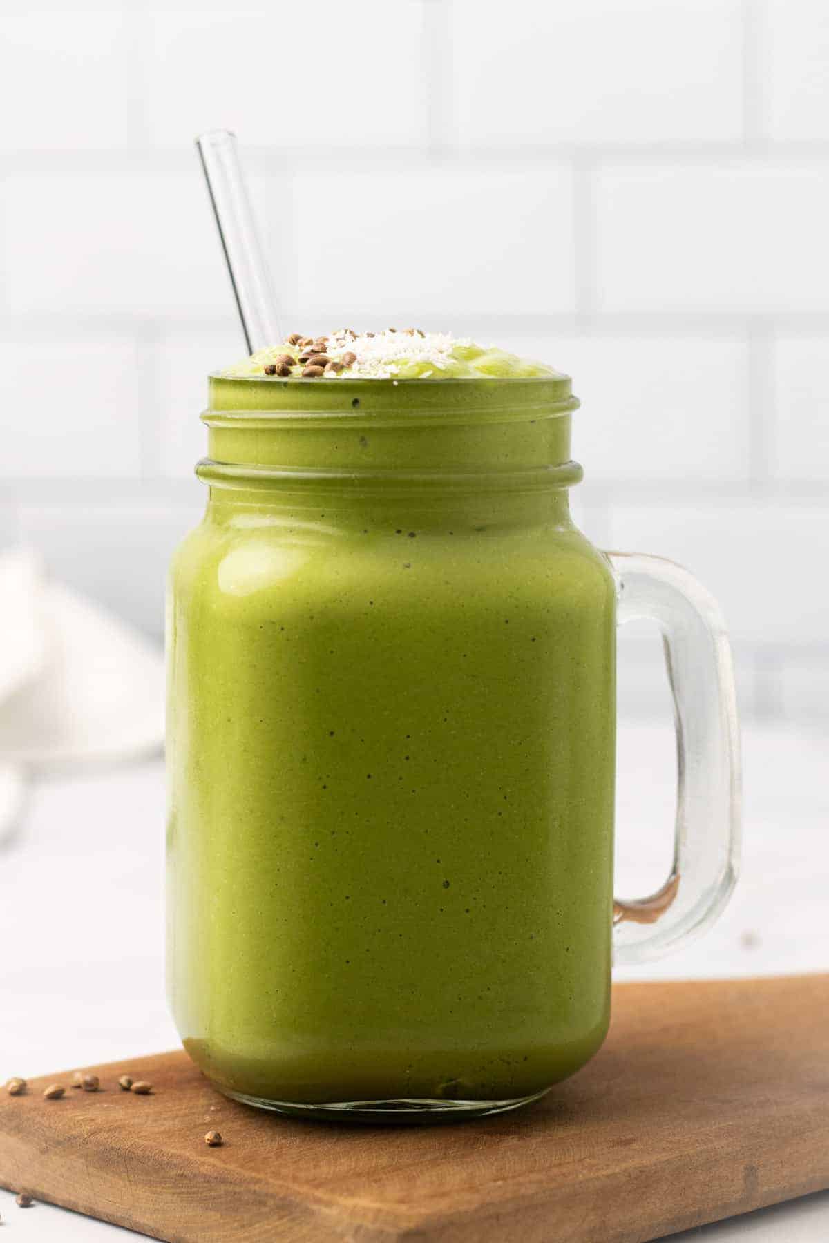 Side view of smoothie in a glass mug with a glass straw sticking out of the top
