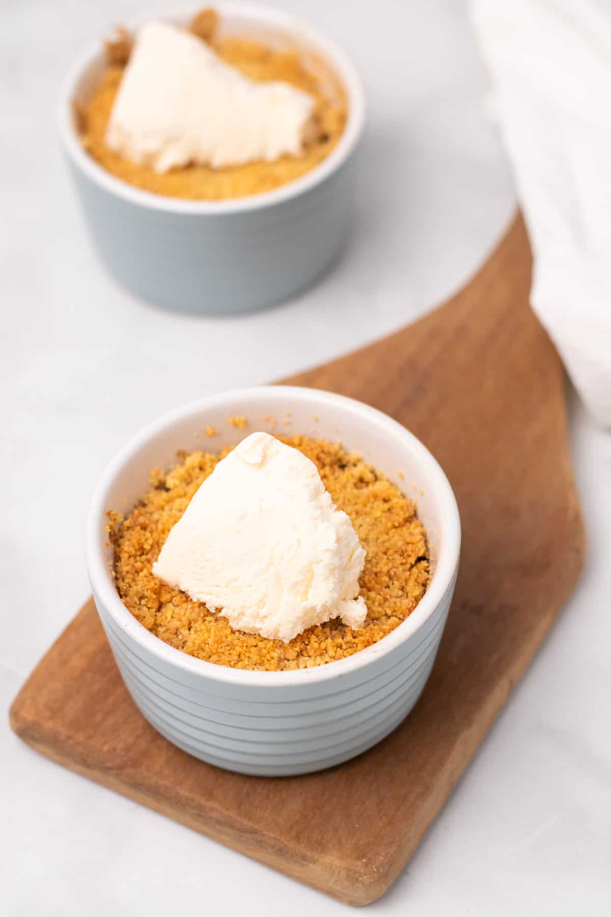 Two ramekins of healthy apple crisp, each topped with a scoop of vanilla ice cream