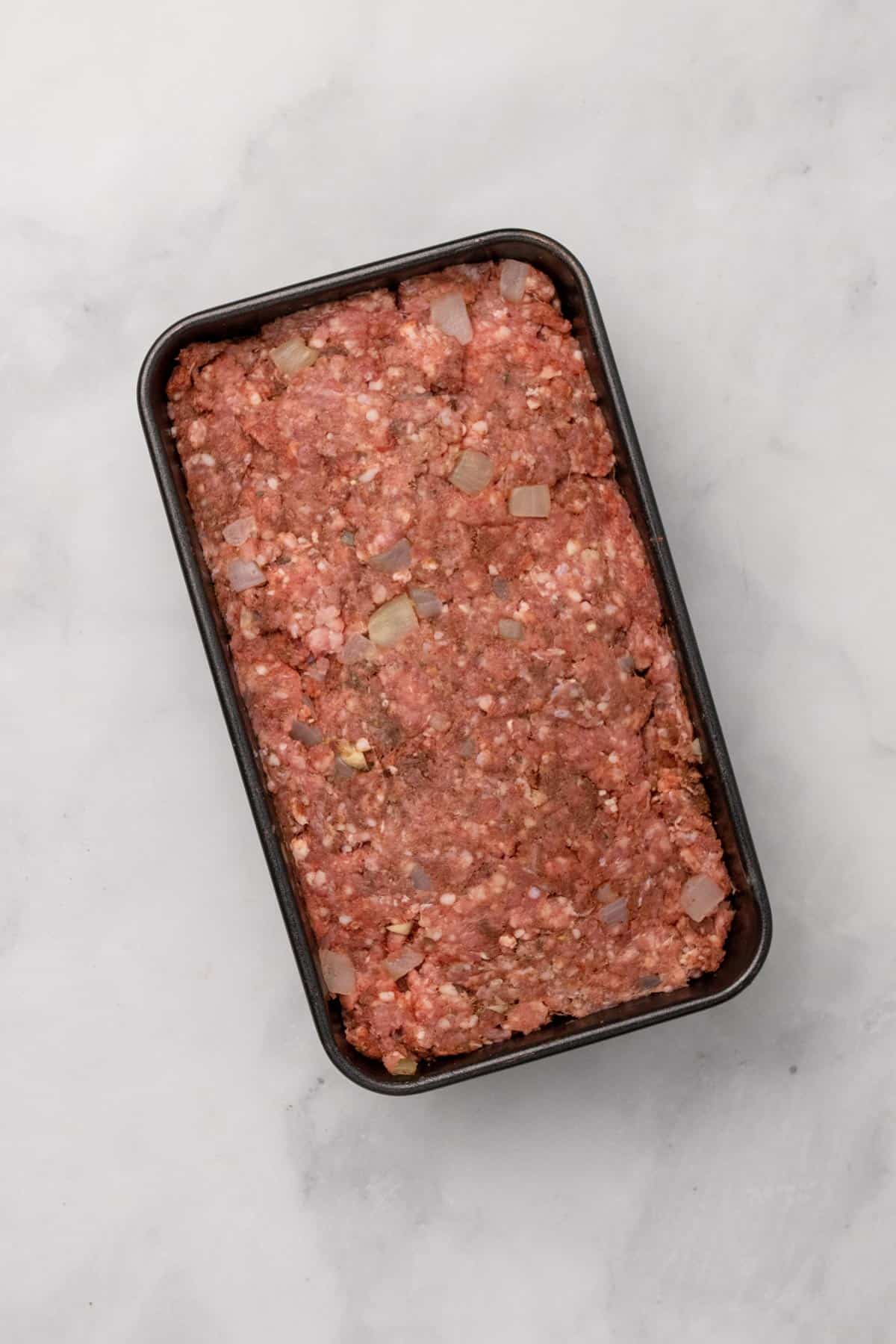 Raw meatloaf ingredients pressed into a baking dish, as seen from above