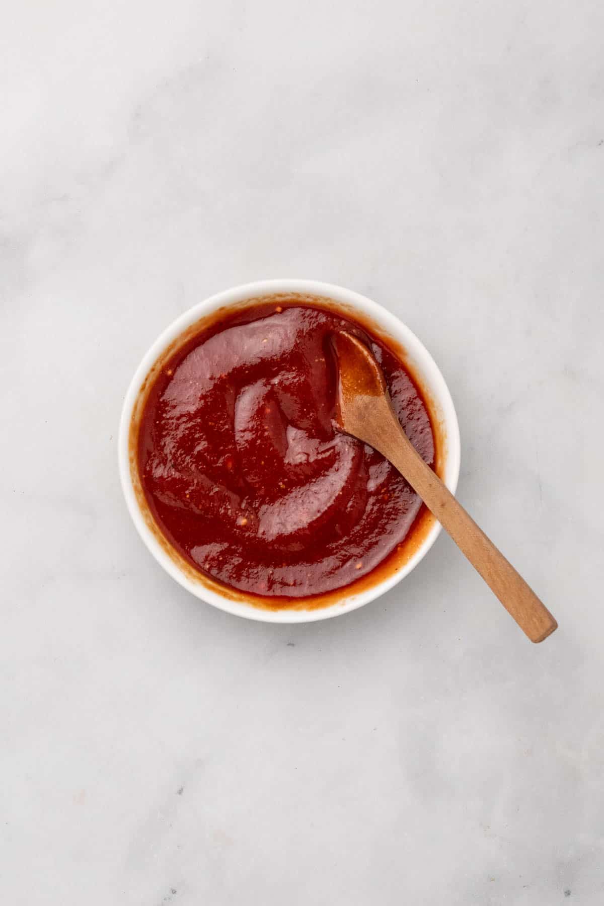 Tomato glaze mixed in a small ramekin with a wooden spoon