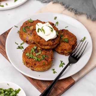 Keto salmon patties on a white plate garnished with parsley and sour cream