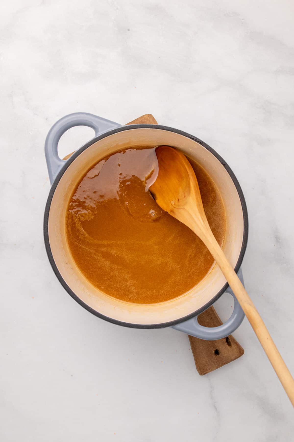 Browned butter mixed with stevia in a white pot with a wooden spoon