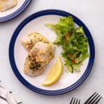 Cod plated with a lemon wedge and salad
