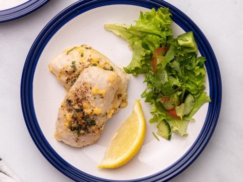 Cod plated with a lemon wedge and salad