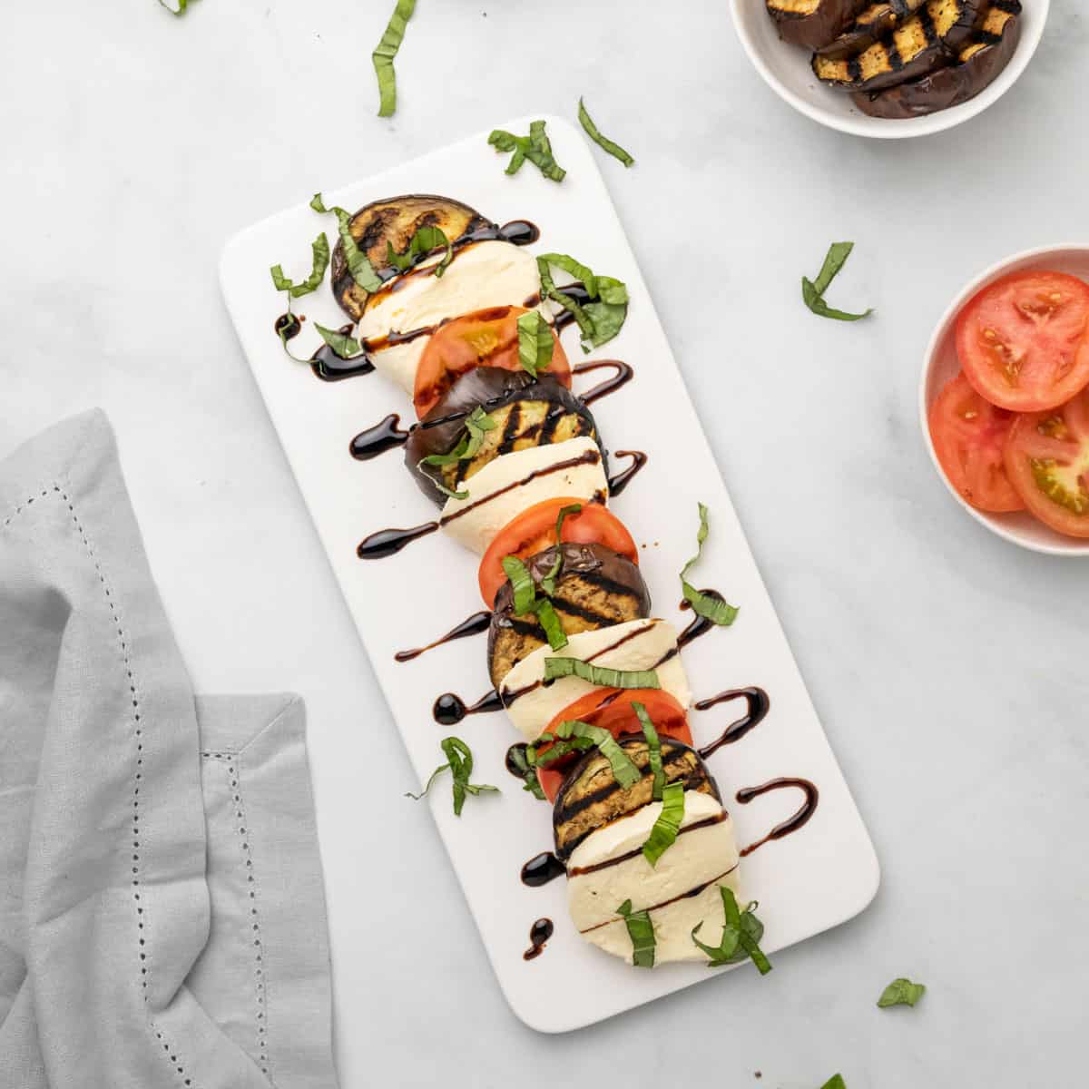 Caprese salad with eggplant on a white serving dish, as seen from above