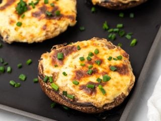 Low carb stuffed mushrooms garnished with chives on a baking tray