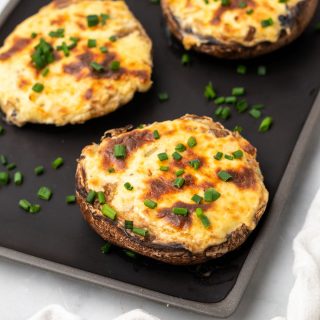 Low carb stuffed mushrooms garnished with chives on a baking tray