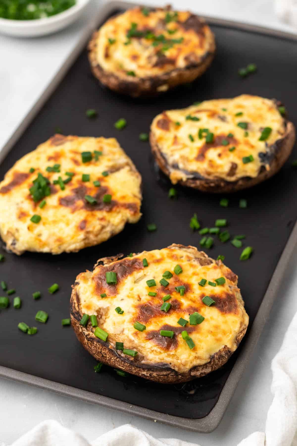 low carb stuffed mushrooms garnished with fresh chives on a baking tray