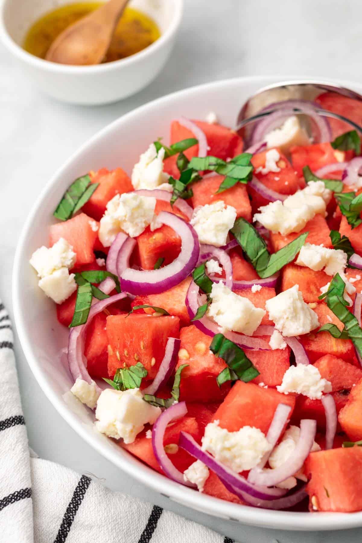 Close up of salad with watermelon, onion, goat cheese, and basil