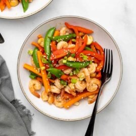 Keto shrimp stir fry in a white bowl with a spoon