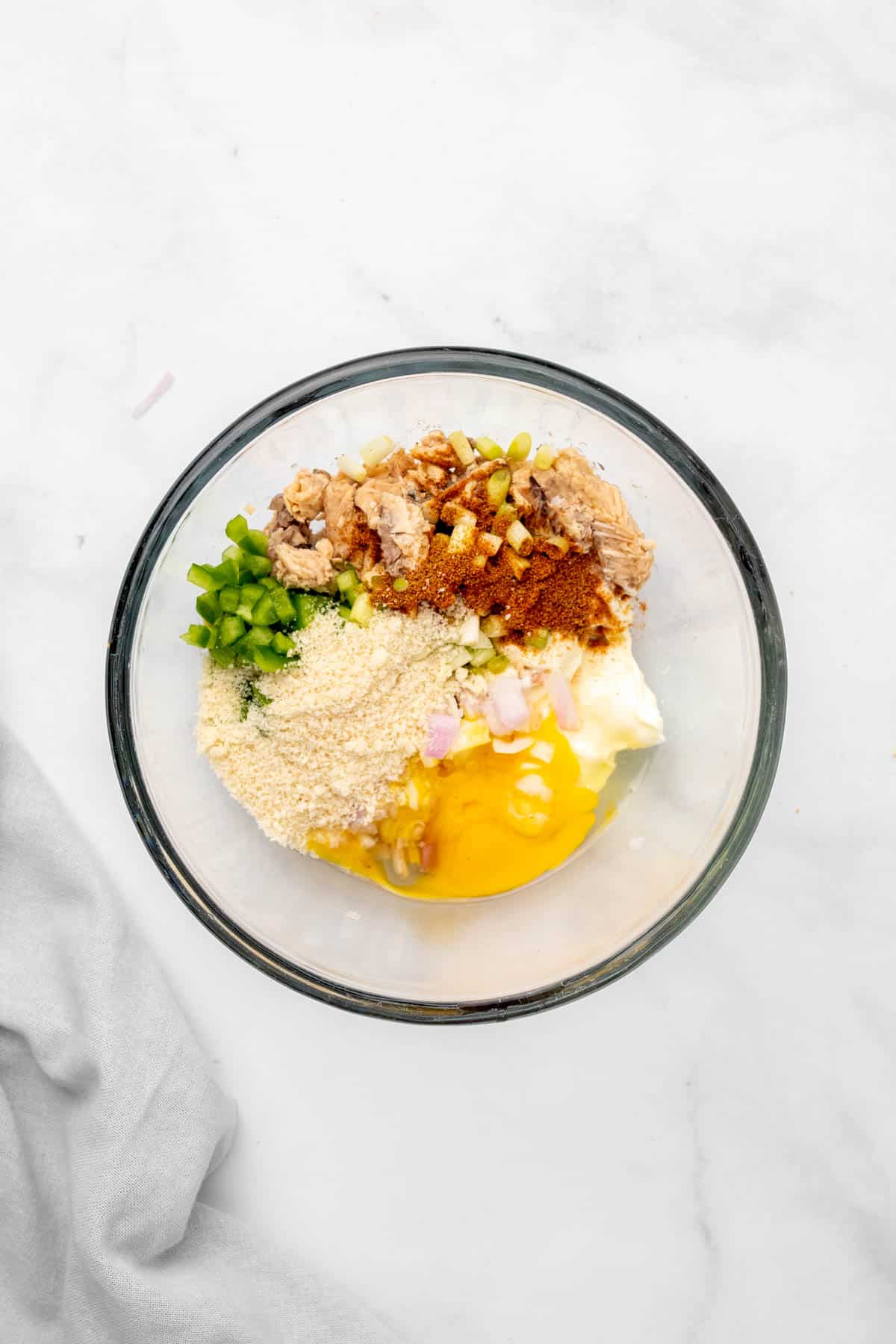 Ingredients for crab cakes, unmixed in a glass bowl