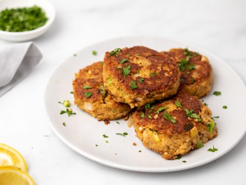 Four Low-Carb Crab Cakes on a white plate garnished with chopped parsley