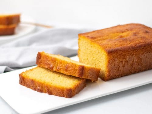 Low-Carb pound cake loaf on a white serving tray with two slices cut