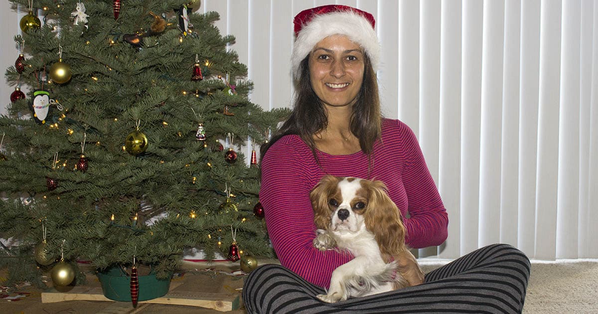 Christel sitting with dog in front of Christmas tree
