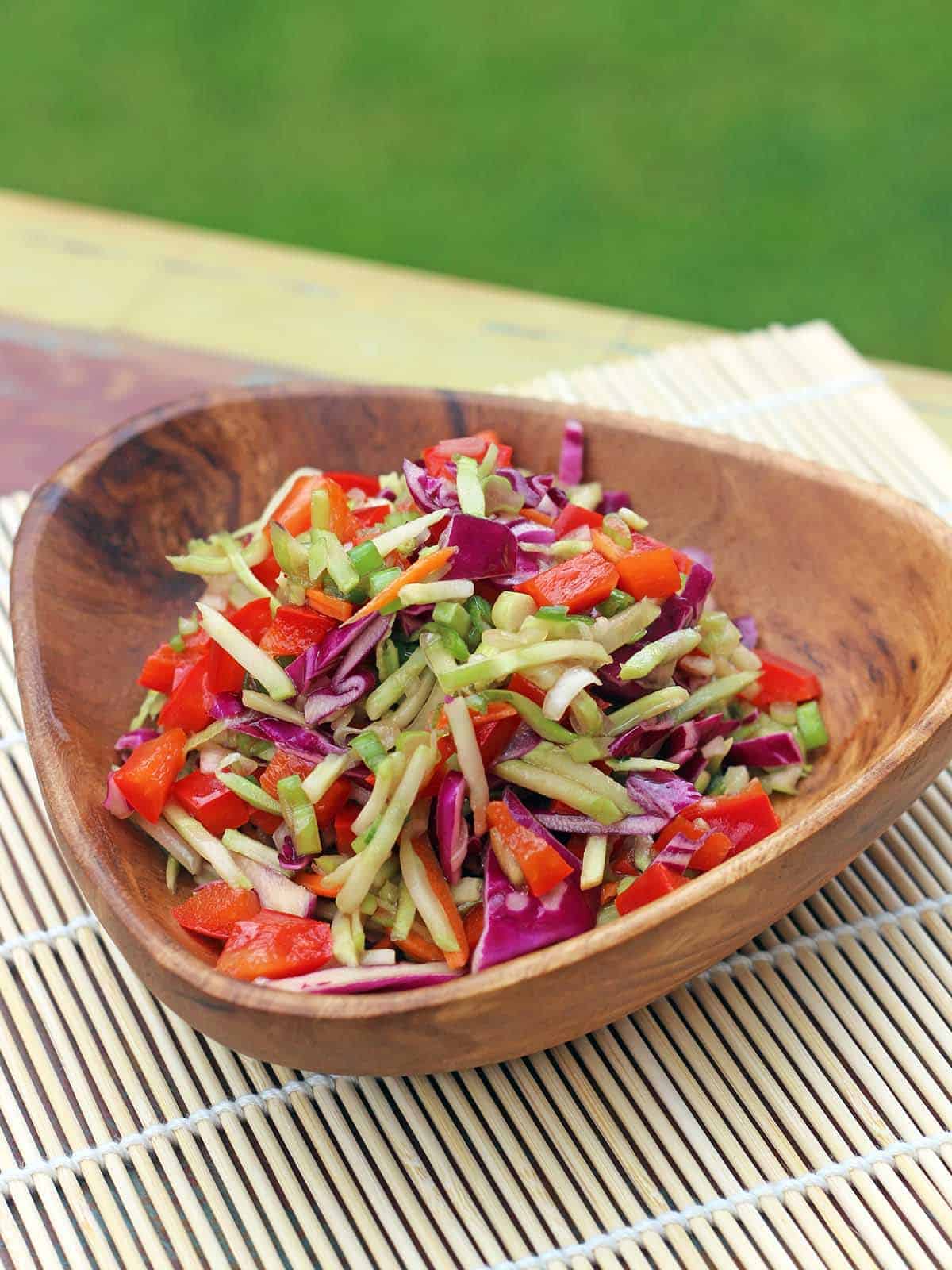 Sesame Broccoli Slaw in a wooden serving bowl on a decorative placemat