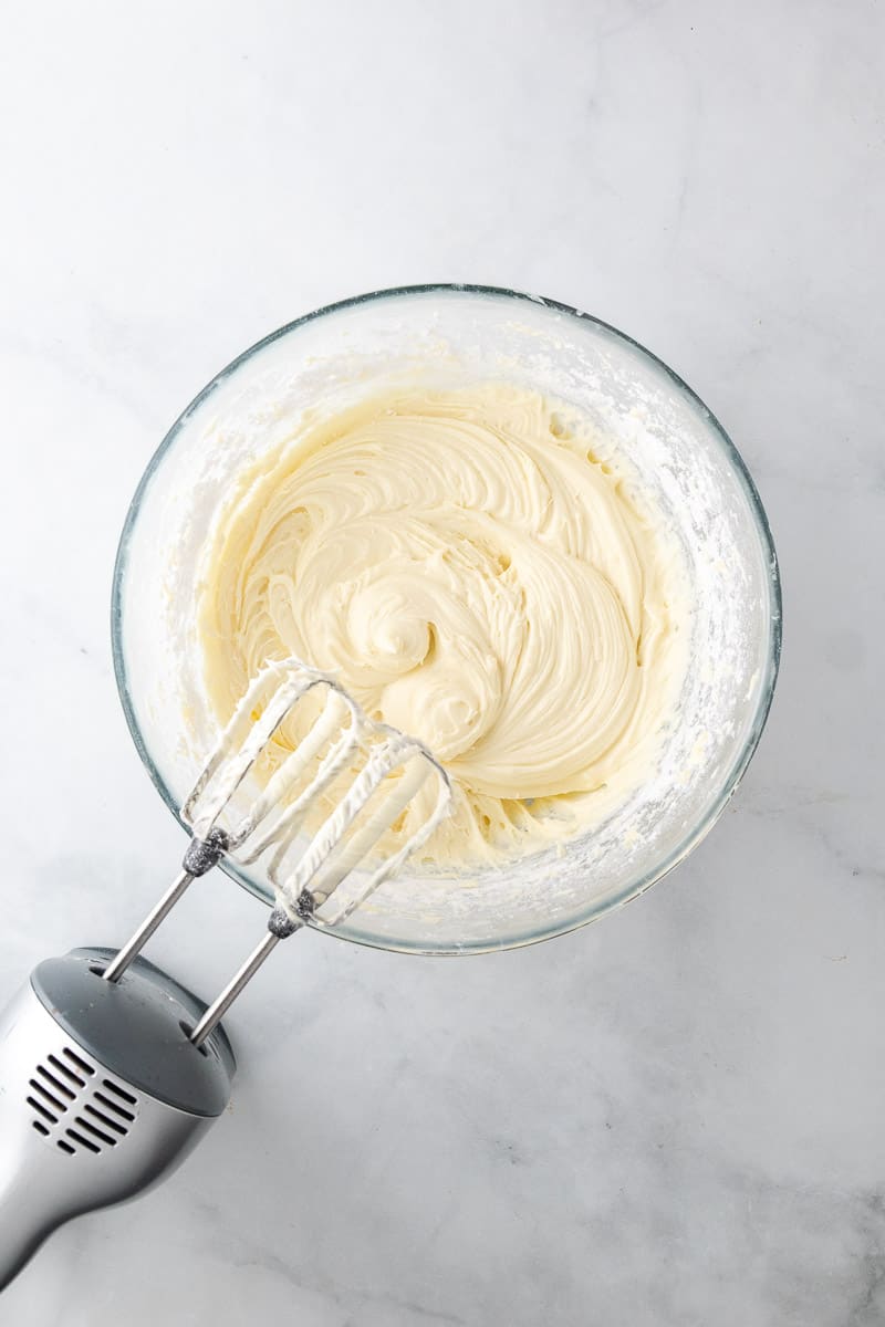 Frosting mixed in a glass bowl with an electric mixer