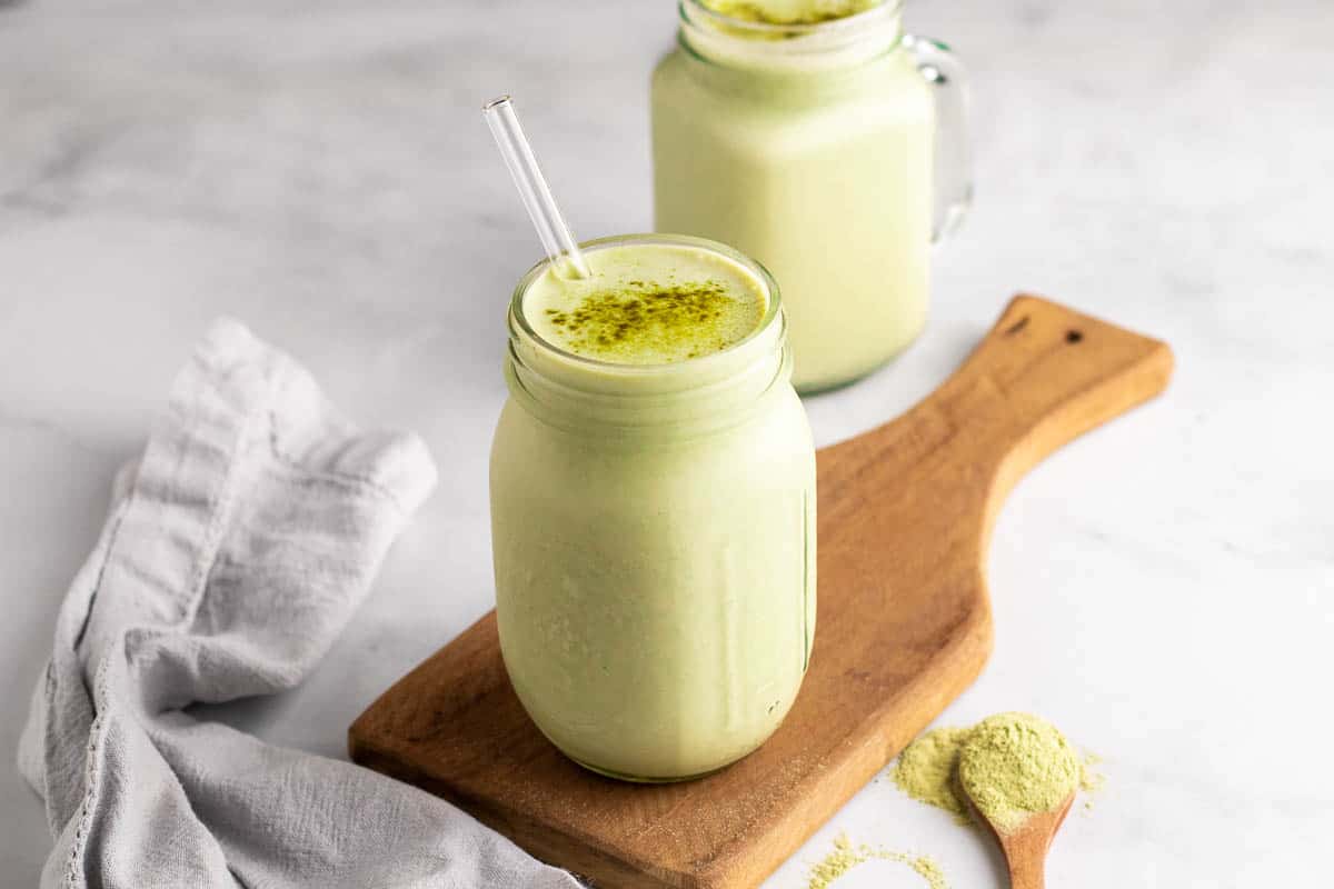 Smoothie in a glass jar with a straw and matcha powder sprinkled on top