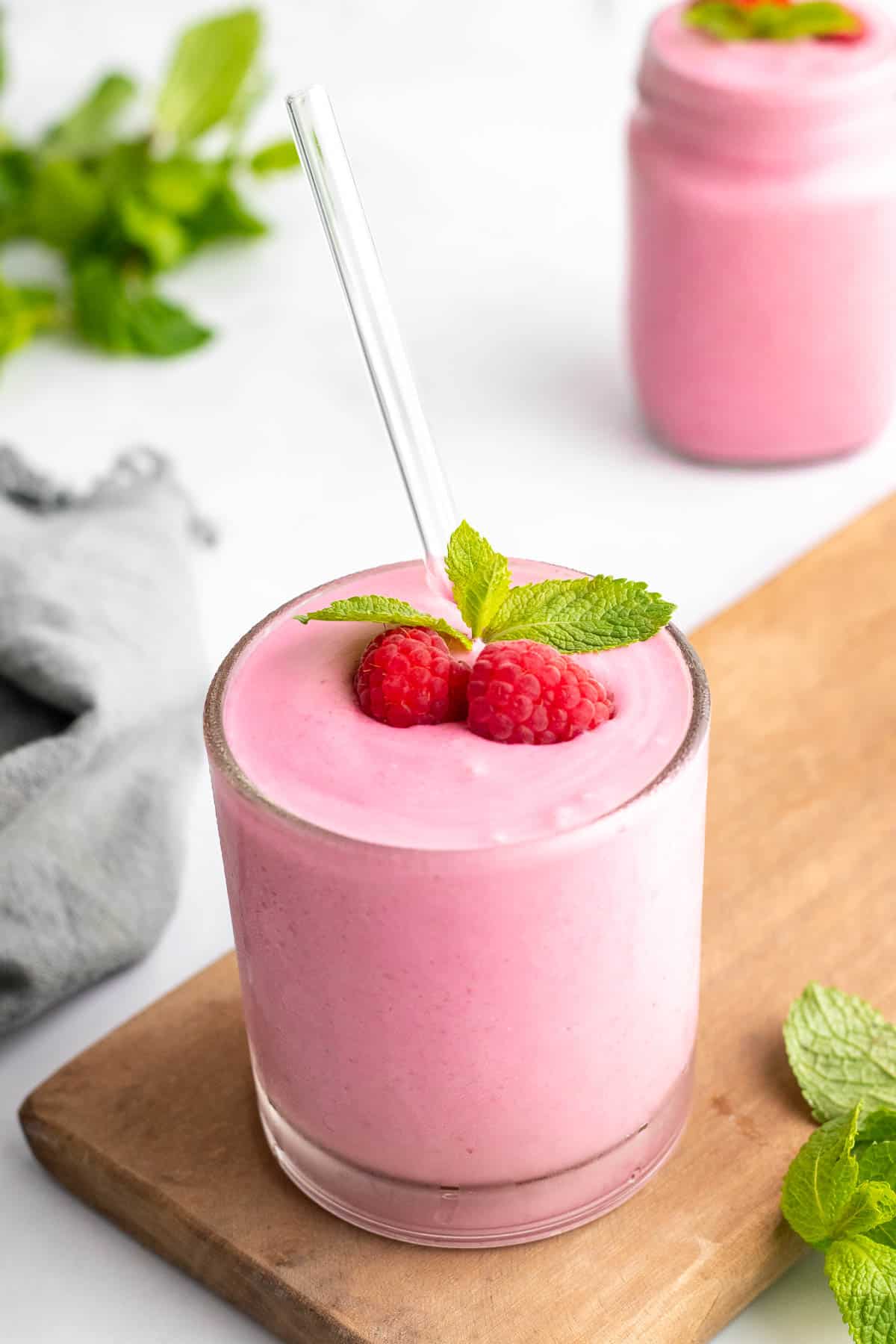 Smoothie in glass with straw, topped with fresh raspberries