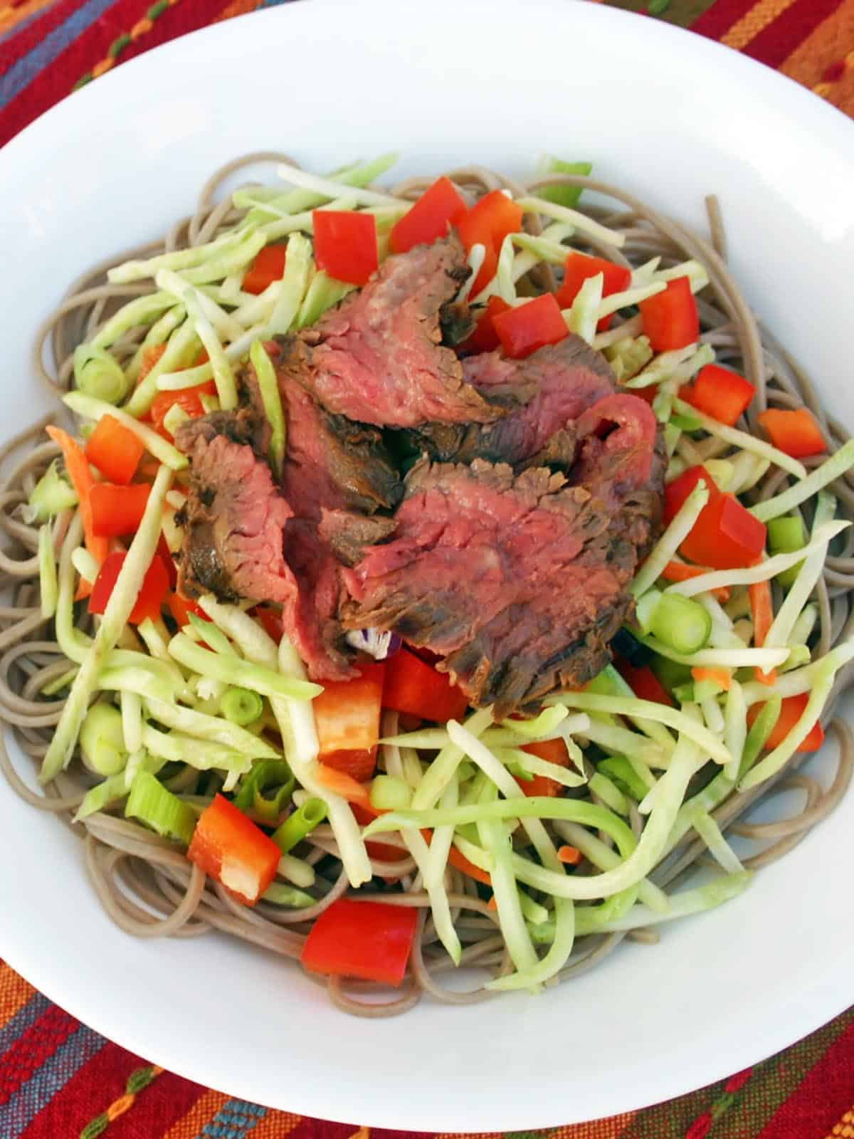Asian steak salad in a white bowl topped with sliced green onion