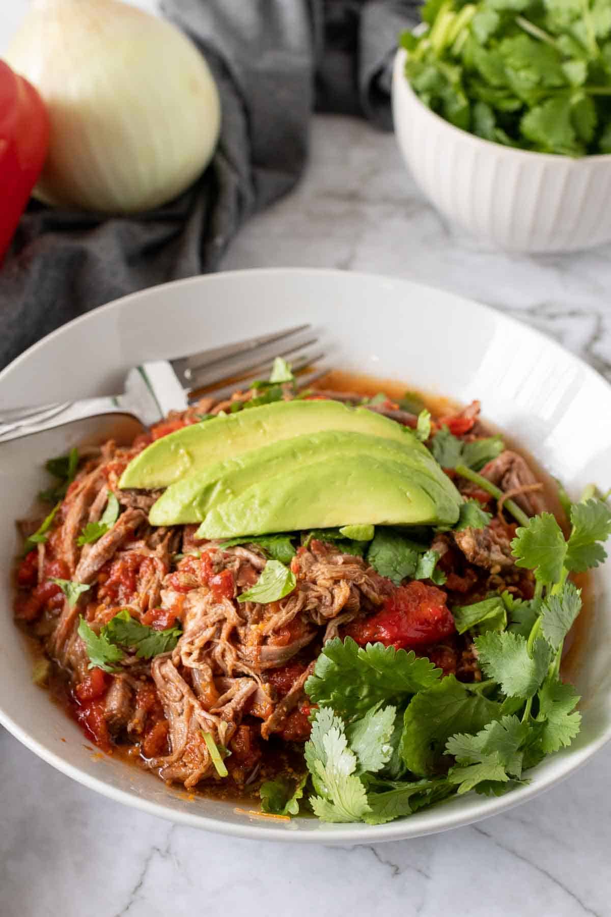 Bowl of Cuban braised beef with avocado and cilantro seen from above 