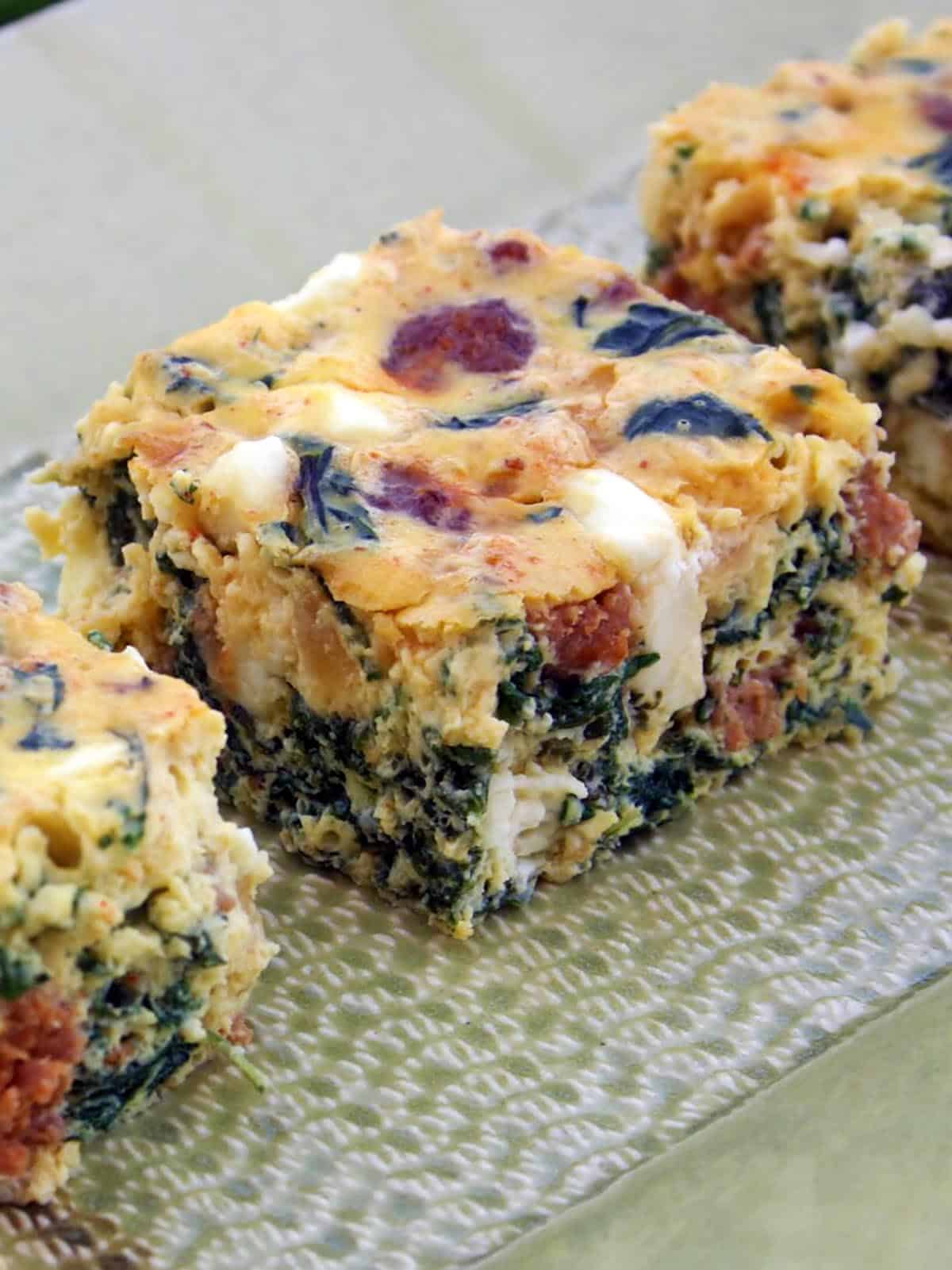 Frittata Bites with Chard, Sausage, and Feta, cut into squares and served on a platter
