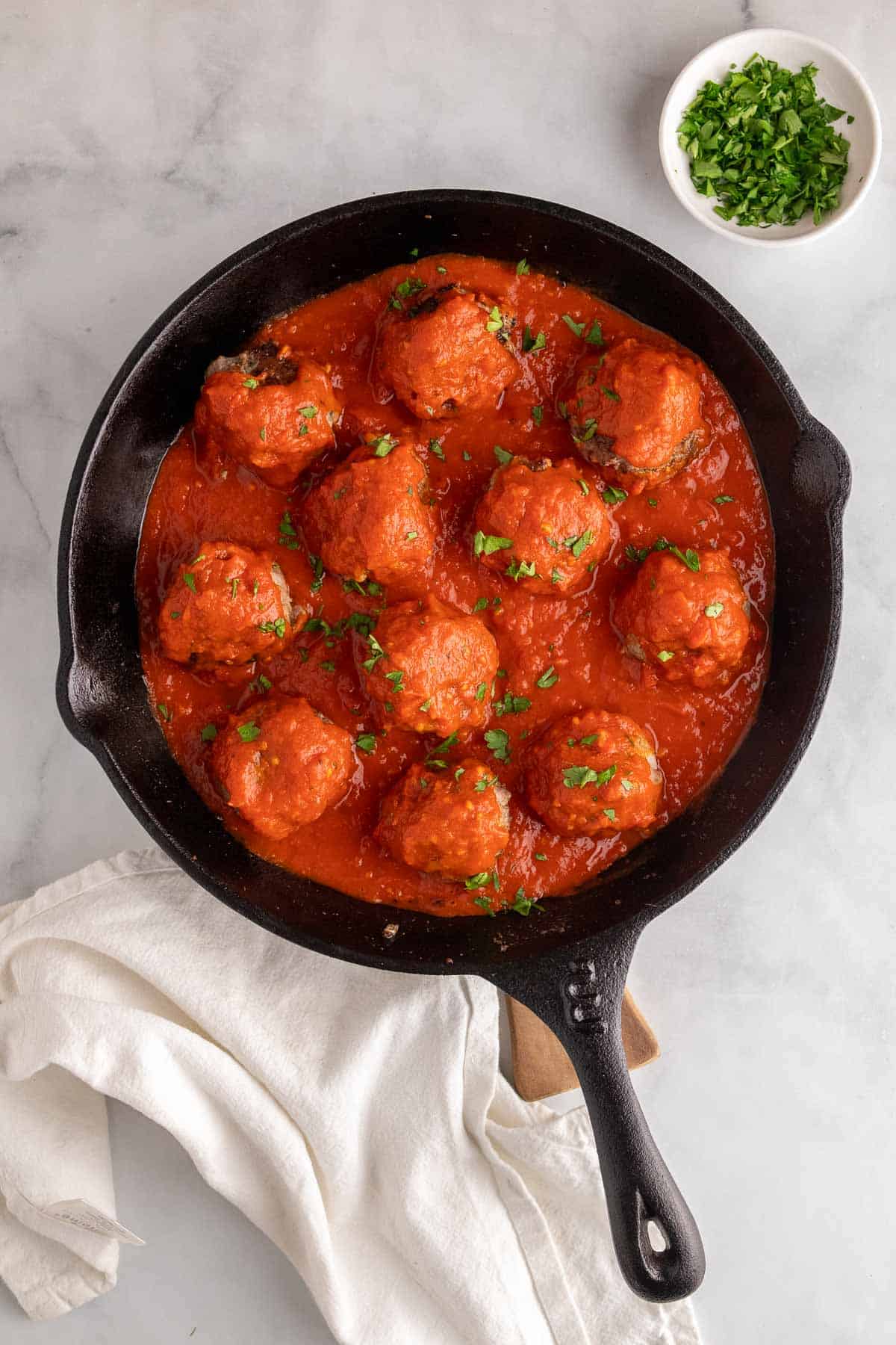 Keto meatballs in a cast iron skillet topped with fresh parsley
