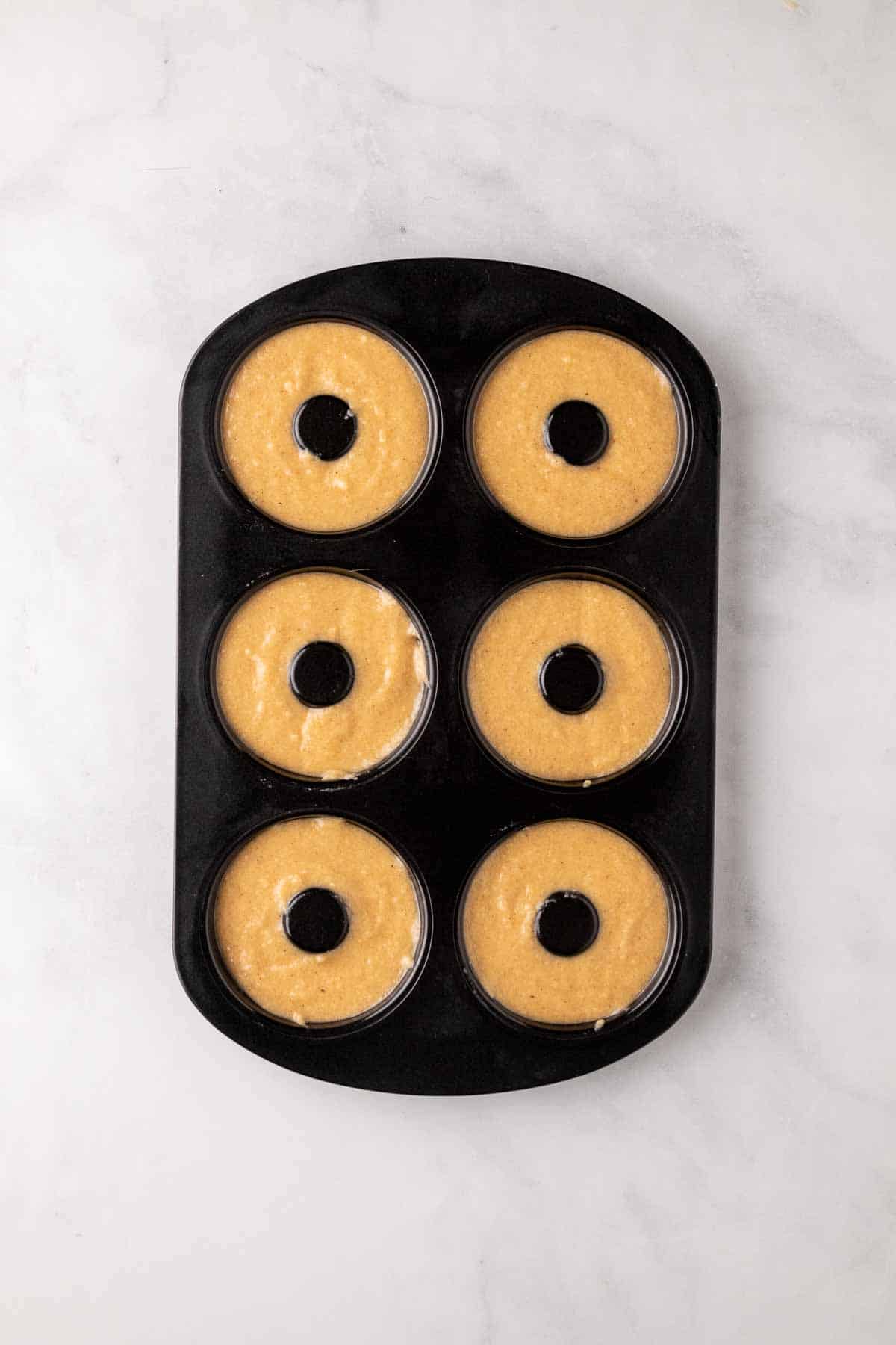 Donut batter in a donut pan, ready to bake