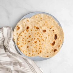 5 homemade keto tortillas on a blue plate, as seen from above