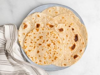 5 homemade keto tortillas on a blue plate, as seen from above