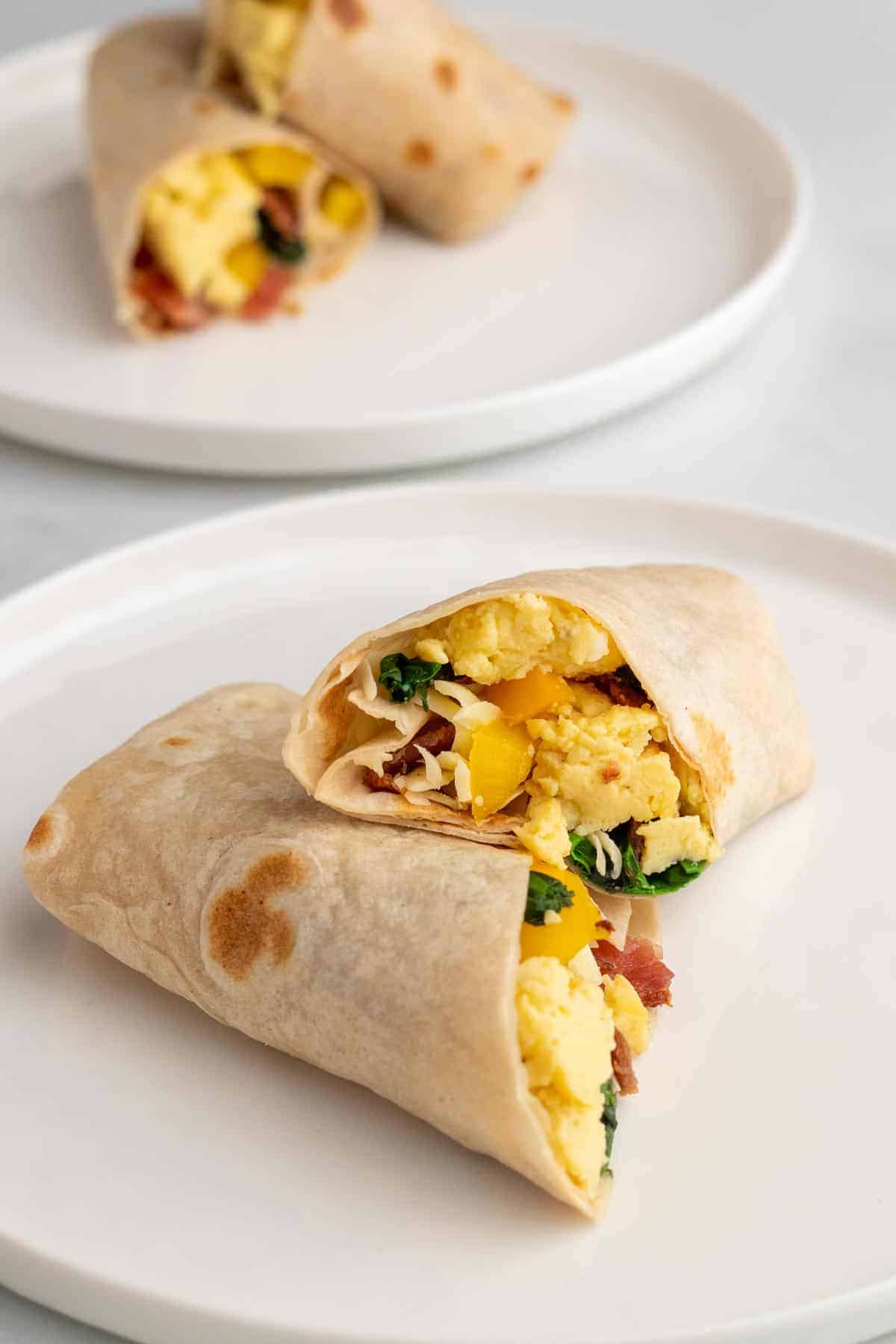 Low-carb breakfast burrito cut into two halves and stacked on a white plate