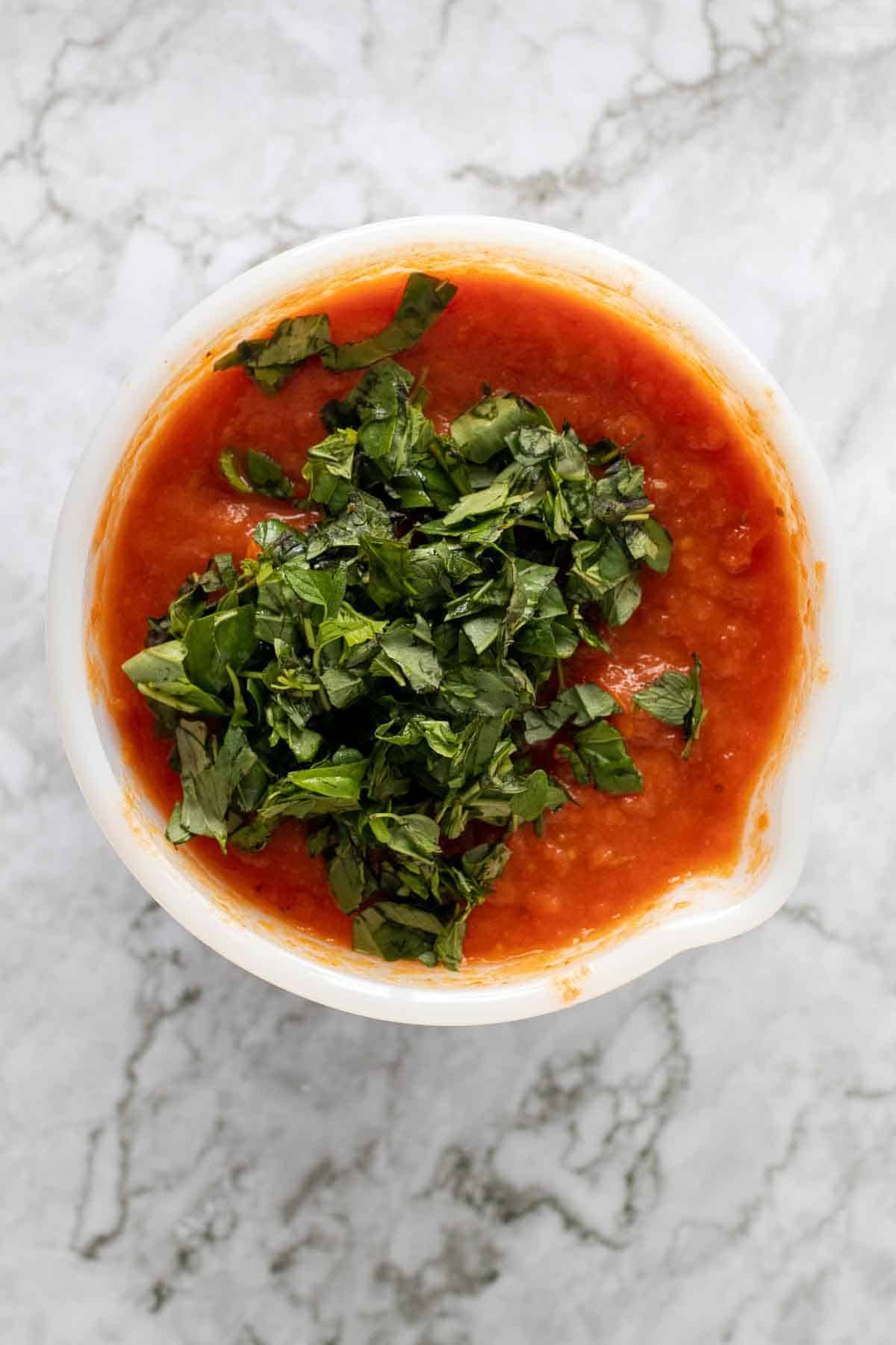 Bowl of oven roasted tomato sauce with chopped basil on top