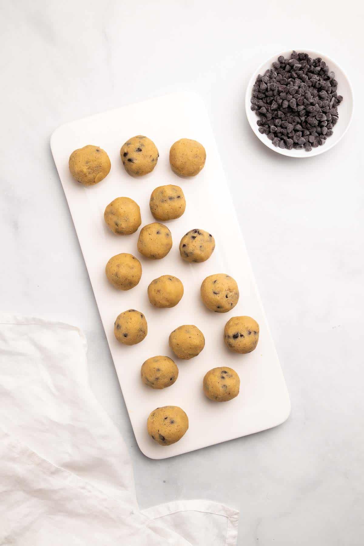 Cookie dough balls on a serving tray next to a ramekin of chocolate chips